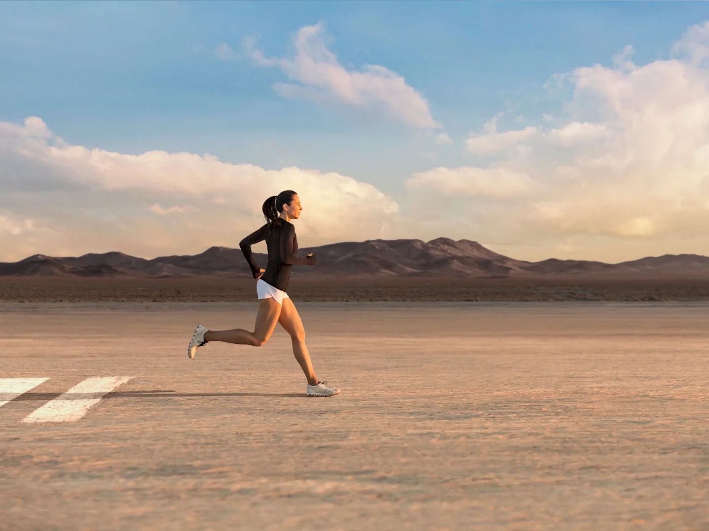 A lone runner crosses a desert flat at dusk